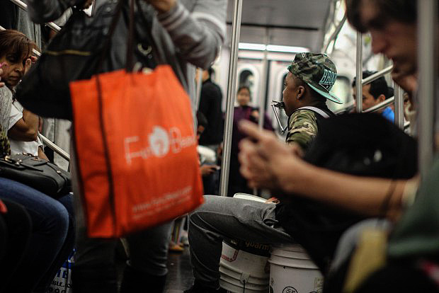 A 13-year old percussionist, Joshua, plays on the 2 train heading to the Bronx. He says he hopes to use donations to buy his own drum set. 